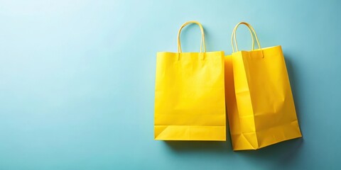 Two bright yellow paper shopping bags partially overlapping on a soft pale blue background with subtle texture and gentle folds , blue background, yellow shopping bag