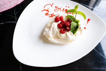 Sweet meringue dessert with berries on a plate in a restaurant.