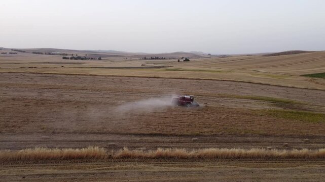 Drone footage of a tractor in a field harvesting wheat during summer harvest season in the hills of Beja in the north of Tunisia.