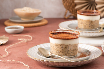 Creamy tiramisu overnight oats and chia pudding topped with yogurt and cocoa powder, served in...