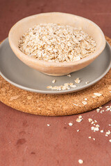 Fine cocoa powder in a metal sieve on a white plate, with some powder spilled around, set against a brown background