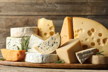 Different types of cheese and rosemary on wooden table