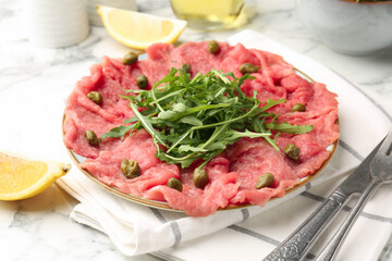Delicious beef carpaccio served on light marble table, closeup