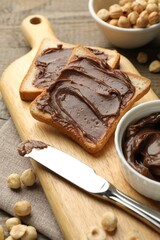 Sandwiches with chocolate butter, hazelnuts and knife on table, closeup