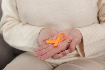 Multiple Sclerosis awareness. Woman with orange ribbon at home, closeup