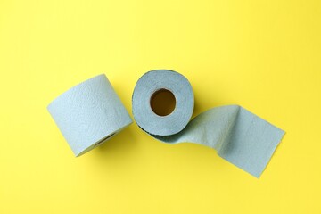 Light blue toilet paper roll on yellow background, top view