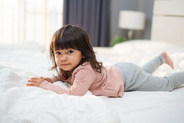 Naklejka premium happy toddler girl smilling on bed