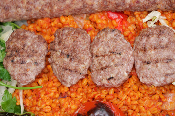 Grilled kebabs served on colorful spiced rice with vegetables