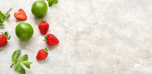 Fresh strawberries, lime and mint on grey background with space for text