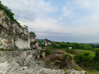 a unique landscape view, most likely a former mining or quarrying area. On the left side of the image, there are towering limestone cliffs