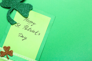 Card with text HAPPY ST. PATRICK'S DAY and paper clovers on green background