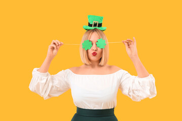 Happy woman with paper clovers on yellow background. St. Patrick's Day
