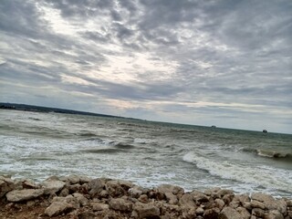 This image shows a wide ocean view with fairly large waves. The sky dominates most of the image,...
