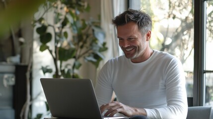 Fototapeta premium Smiling Man Working on Laptop Indoors