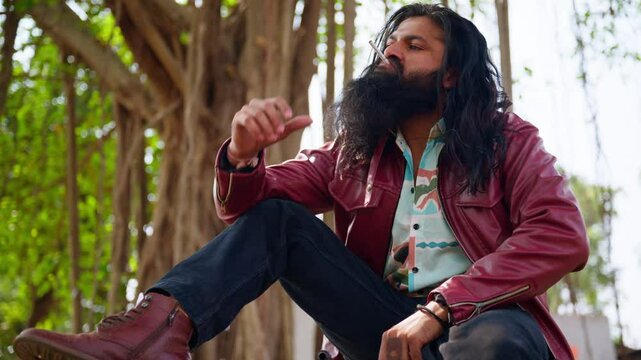Bearded don with long hair light cigarette in forest area