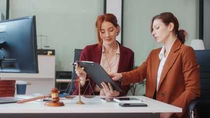 Two Caucasian women meet at a table, discussing legal matters. As lawyers, they advise clients on rights, responsibilities,business issues, representing them in criminal, civil, and regulatory cases