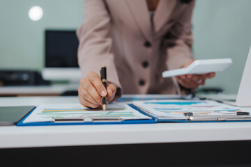 An Asian businesswoman accountant calculates invoices, taxes, interest, loans using a...