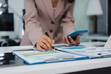 An Asian businesswoman accountant calculates invoices, taxes, interest, loans using a calculator,working online to guide clients through financial planning ensure a smooth loan process for success