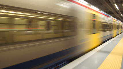 Obraz premium Blur of a Speeding Train Passing Through a Station, Capturing the Motion and Energy of Modern Urban Transportation.