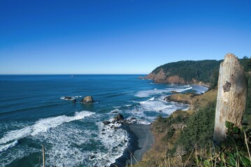 View of Oregon pacific ocean coastline including a shallow sandy beach covered with wave swells on a clear sunny. © Kay