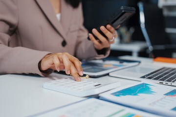 An Asian businesswoman accountant calculates invoices, taxes, interest, loans using a...