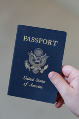 Hand Holding United States Passport Against Neutral Background


