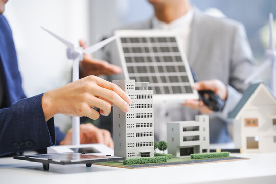 Two Asian businessmen meet at the table with wind power engineers to discuss renewable energy solutions. They exchange ideas on wind turbines, solar energy,simulations for sustainable development