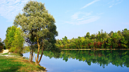A blue lake surrounded by forests, trees and grass. A freshwater lake with clean and clear water under a blue sky. A clear water lake considered a pearl of nature