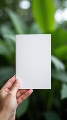Hand Holding Blank White Brochure with Lush Green Background &ndash; Generative AI
