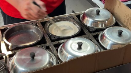 A close-up of a vendor making peanut pancakes, aka apam balik, min jiang kueh or tai kau min on a hawker street food stall in Penang, Malaysia