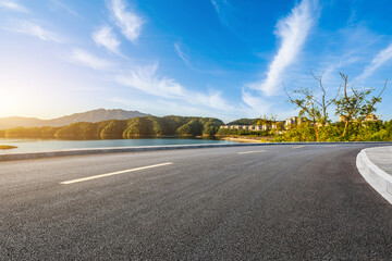 Asphalt road and lake with islands nature landscape at sunrise