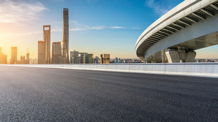 Asphalt road and bridge with modern city buildings at sunrise in Shanghai