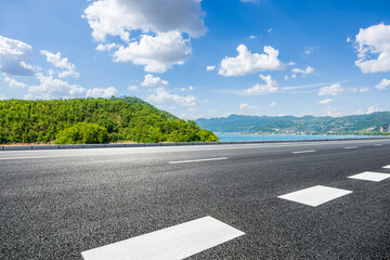 Fototapeta premium Empty asphalt road with beautiful lake and mountain view under blue sky