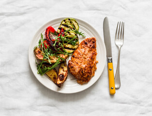 Baked turkey breast, grilled vegetables - potatoes, zucchini, pepper, arugula - a delicious balanced lunch on a light background