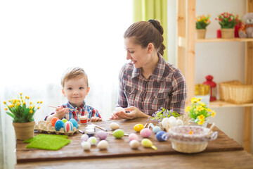 A woman and her child are happily decorating Easter eggs together