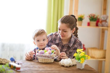 A woman and a child are happily decorating Easter eggs together