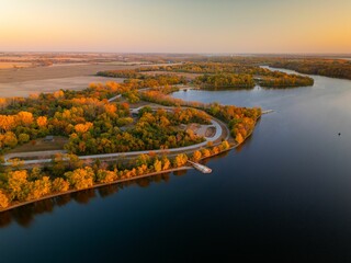 Fototapeta premium Aerial view of autumn landscape with vibrant foliage surrounding Big Creek State Park, Polk City, IA
