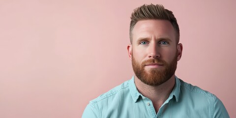 Obraz premium Confident Young Man with Beard Against a Soft Pink Background