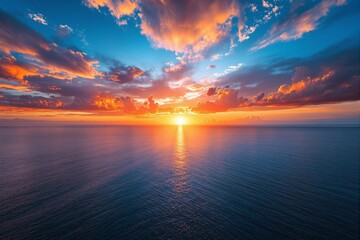 Obraz premium Vibrant ocean sunset with fiery clouds and serene water reflecting light.