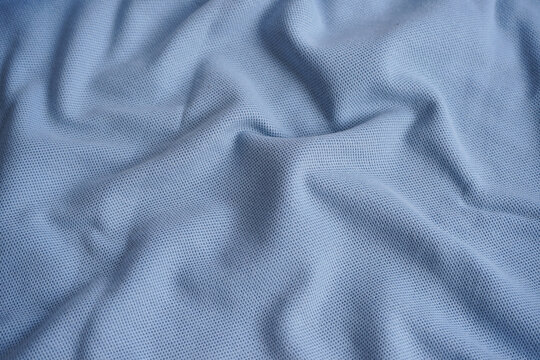 Texture of turquoise blue cotton pique fabric. Flat lay style, close up. Commonly use for t- shirt. Woven fabric characterized by a pattern of raised parallel cords or geometric designs. 