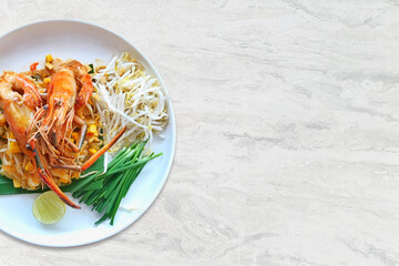 Pad Thai  Stir-fried rice noodles with river prawns in sauce on a plate on a marble table