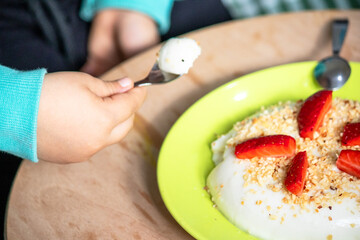 A little boy took a spoonful of strawberry cake from a plate. Dessert prepared with honey for...