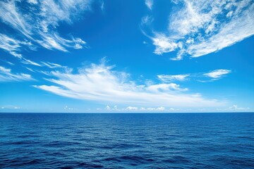 Obraz premium Vast ocean under a bright blue sky with wispy clouds. Perfect for travel, serenity, and summer themes.