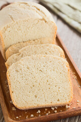 Slices of fresh homemade white bread made by a bread making machine, served on wooden board (Selective Focus, Focus one third into the image)