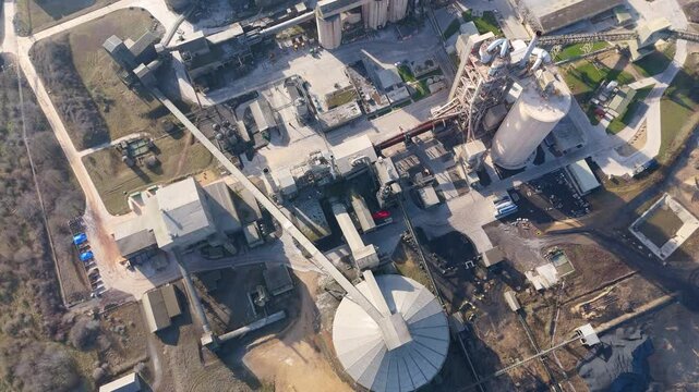 Aerial drone fly over close up of industrial processing warehouse facility refinement aggregates cement production smoke stacks towers in England UK on a sunny day 