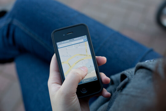 Woman navigating maps using iPhone 4 by Apple.