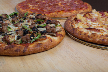 Fresh combination, Hawaiian and pepperoni pizzas on a wooden table.