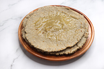 Jowar flour flatbread known as bhakar or jawari bhakri. served with ghee, spicy garlic or lasun chutney, bhindi or lady finger sabji. farmer's food. Maharashtrian village food. copy space.