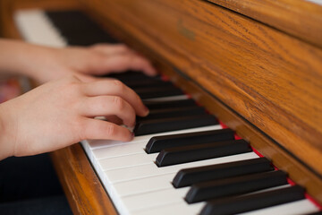 Obraz premium Child's Hands Playing Wooden Piano Keys