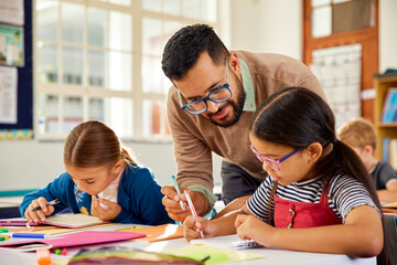 Teacher helping schoolchildren during lesson in classroom